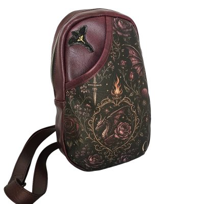Angled view of the Rider’s Vow sling bag showing the dragon and rose print, wine faux leather and adjustable strap