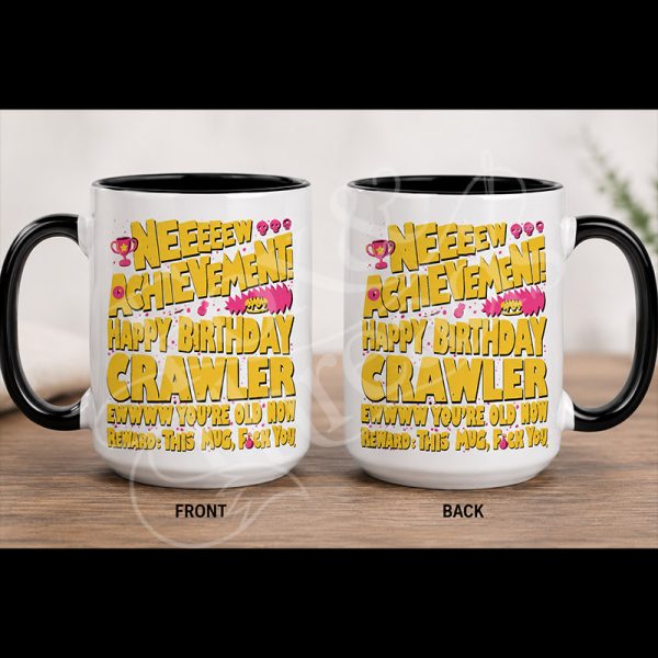 New Achievement Happy Birthday Crawler 15 oz white mug with black handle and pink and yellow artwork